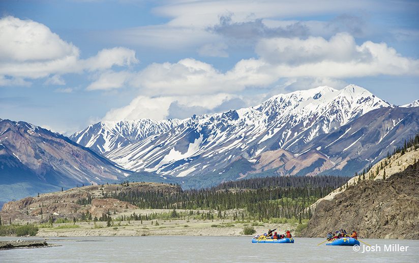 Rafts line up for a moment beneath towering peaks on the Alsek River.