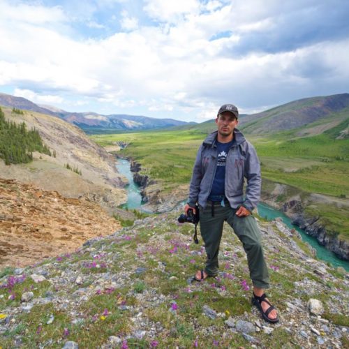 a man standing on a rocky hill with a camera in his hand