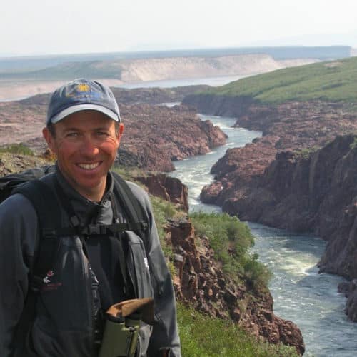 a man standing on a cliff with a river in the background