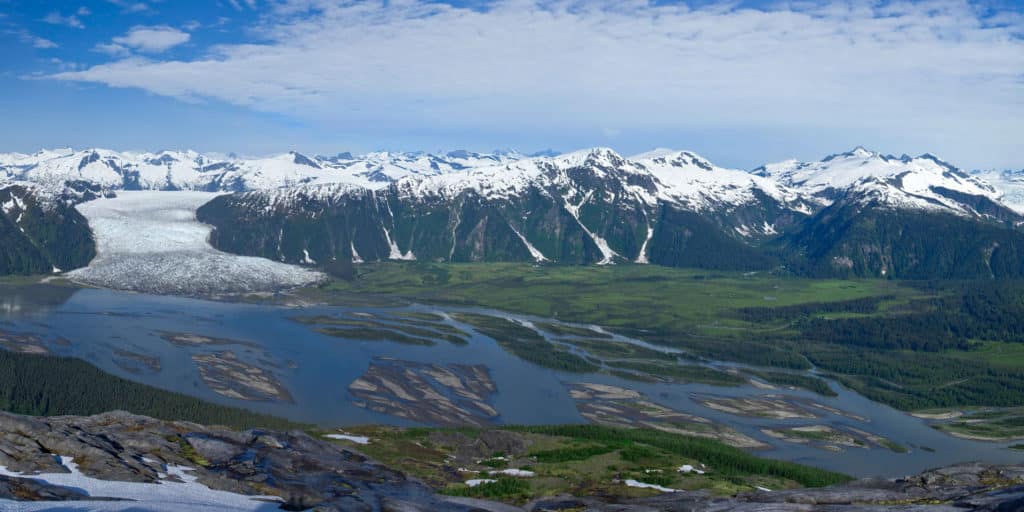 a river running through a valley with snow covered mountains
