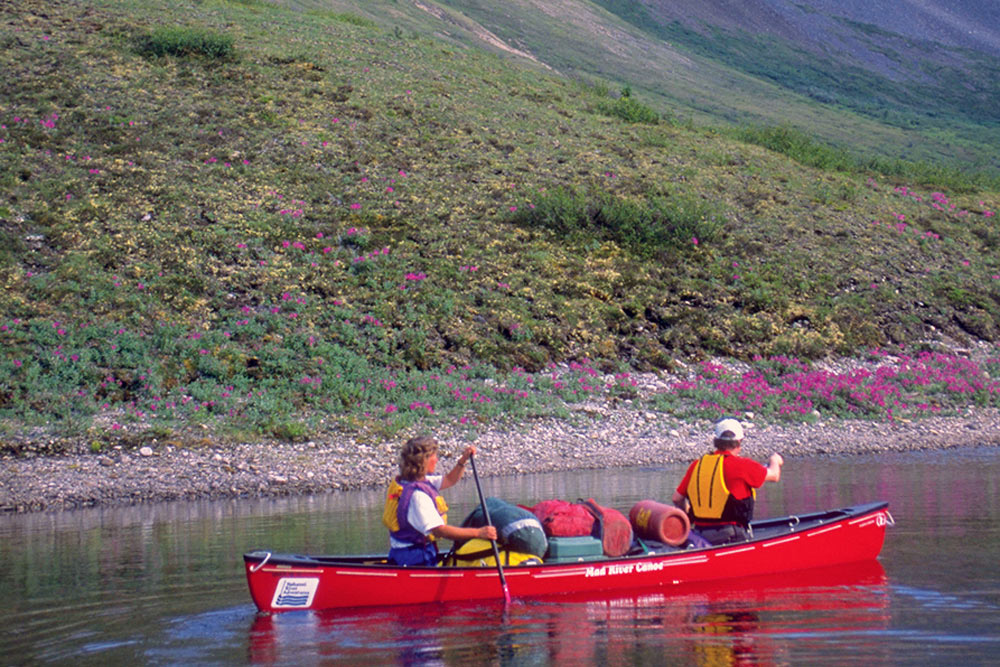 A couple paddling a canoe on the Snake River in Yukon, Canada through the Peel Watershed.