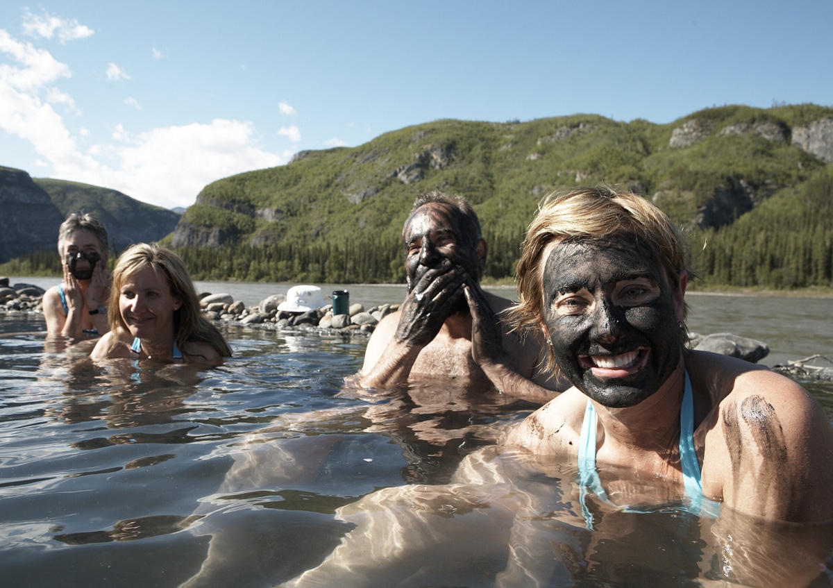 a group of people in a lake with black mud on their faces