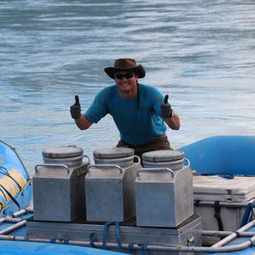 a man in a hat giving thumbs up on a raft