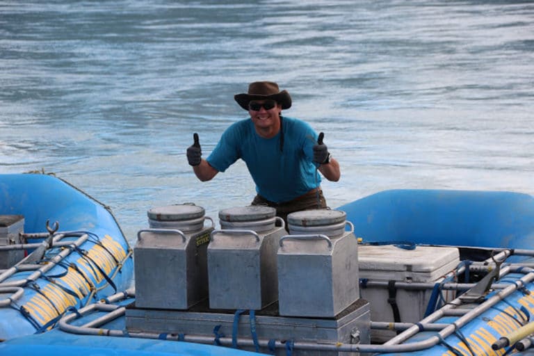 a man in a hat giving thumbs up on a raft
