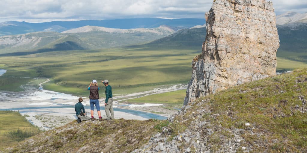 a group of people standing on a mountain looking at a valley