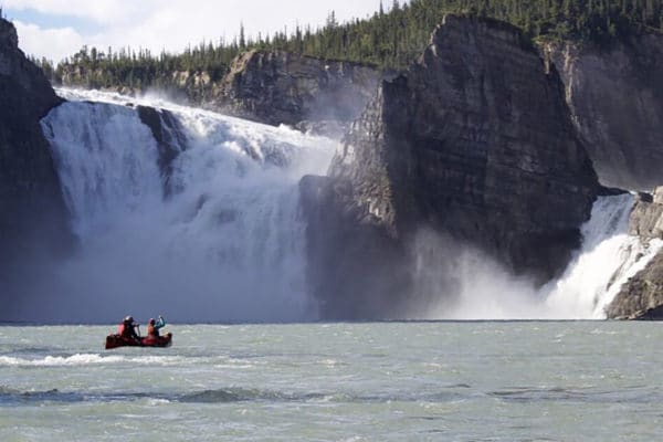 Couple paddling canoe next to Virginia Falls on the Nahanni River