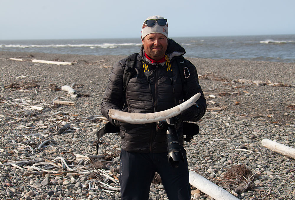 Photographer holding a mammoth tusk that he found on Nunaluk Spit on the Firth River.