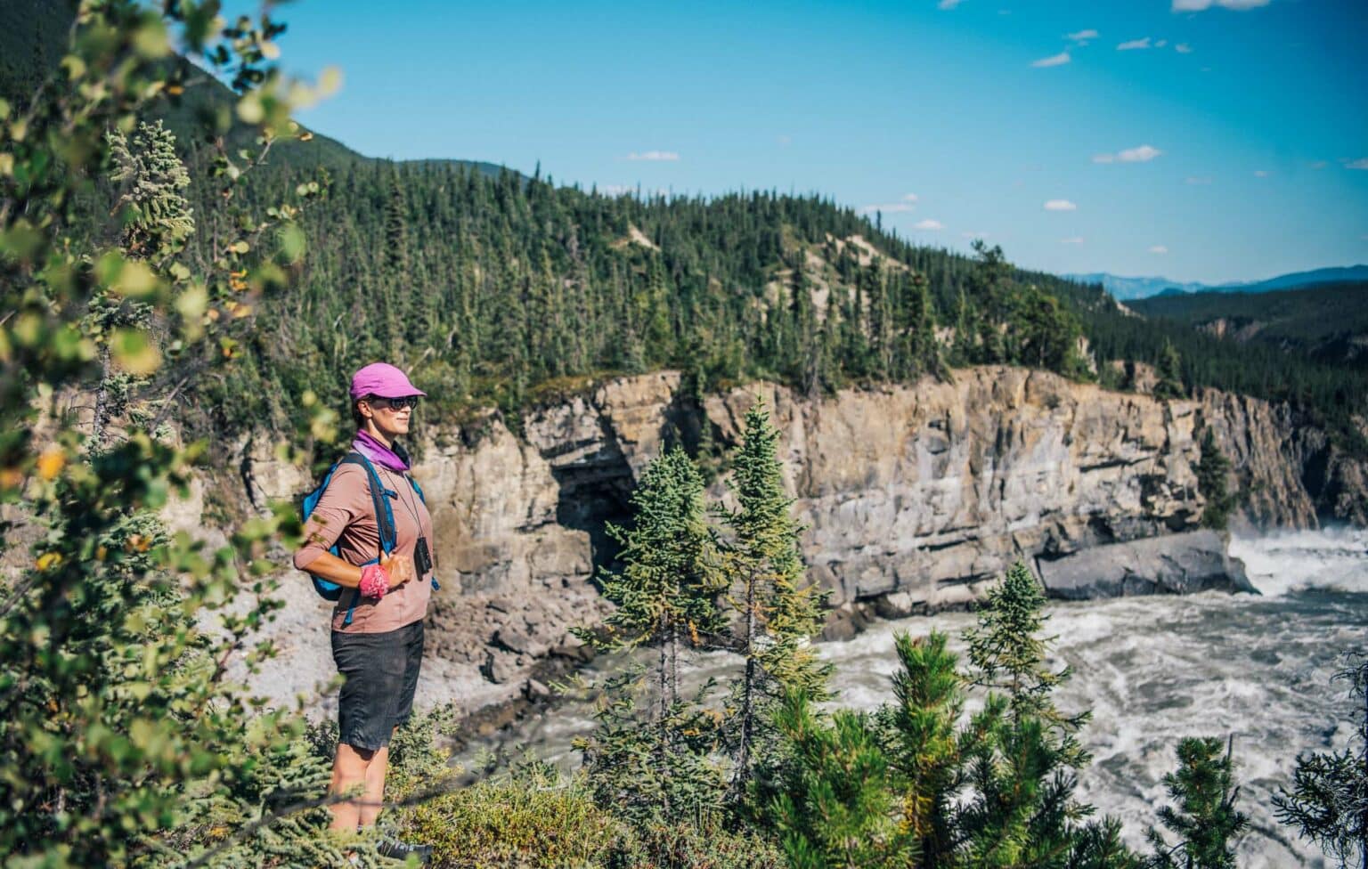 a woman standing on a cliff overlooking a river
