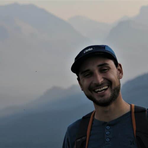 a man smiling in front of mountains