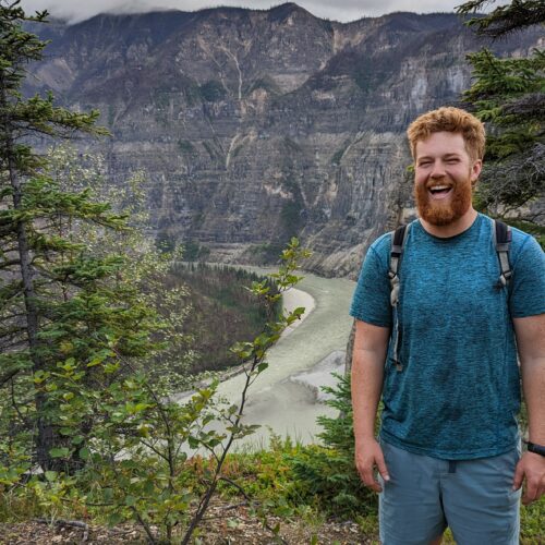 a man standing on a hill with a river in the background