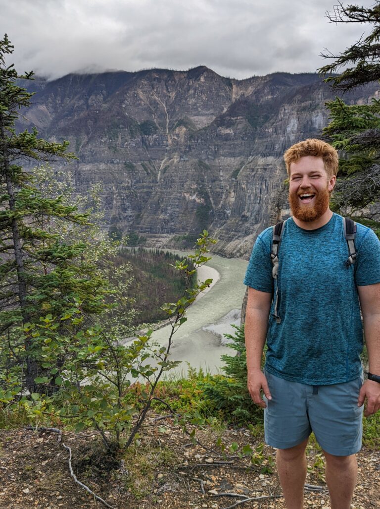 a man standing on a hill with a river in the background