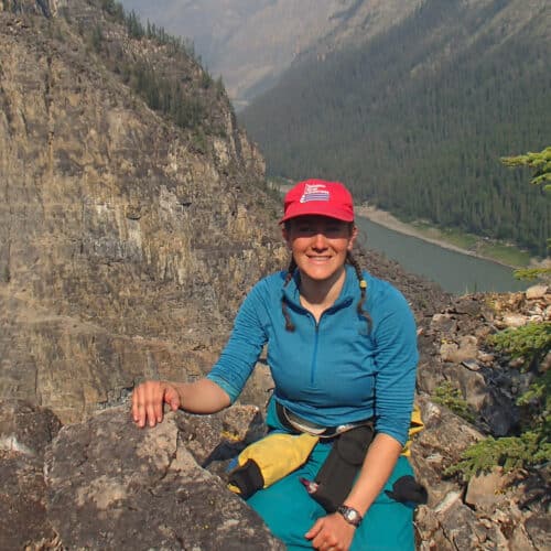 a woman sitting on a rock with a river in the background