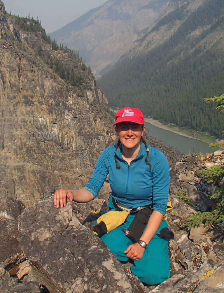 a woman sitting on a rock with a river in the background
