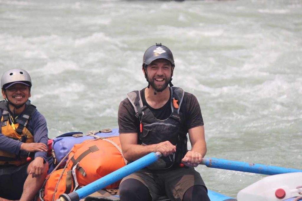 a man in a boat with a blue pole