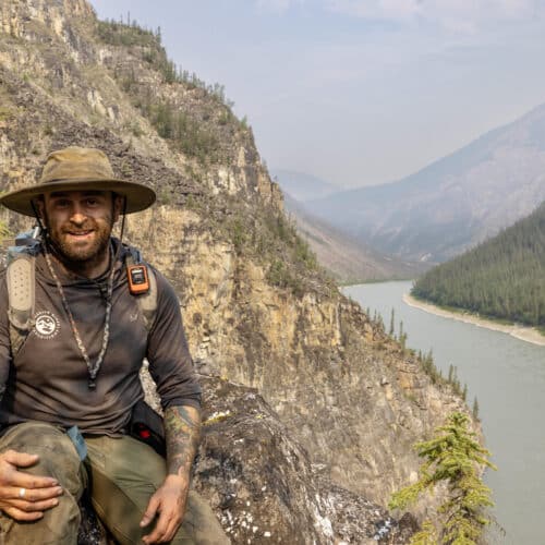 a man sitting on a rock with a river in the background