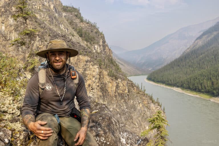 a man sitting on a rock with a river in the background