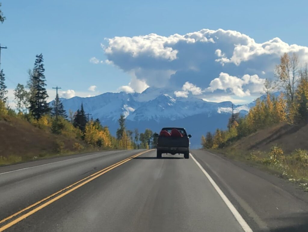a truck on a road with mountains in the background