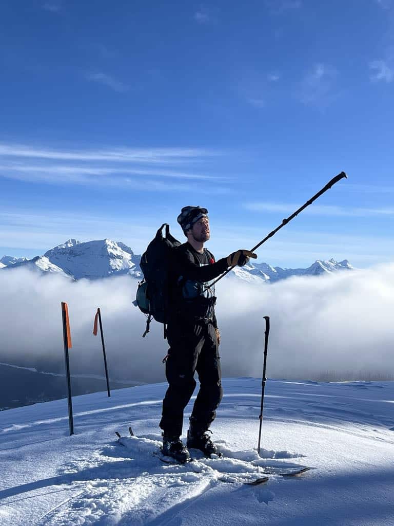 a man standing on a snowy mountain with a pole
