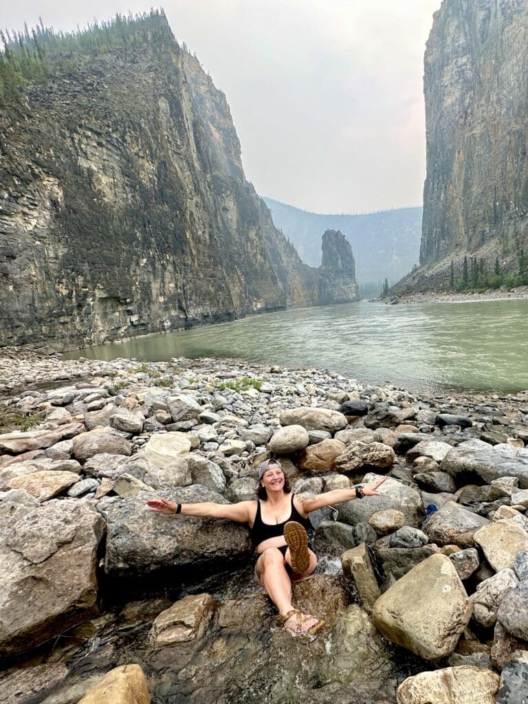 a woman sitting on rocks by a river