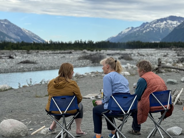 Three people relaxing by river