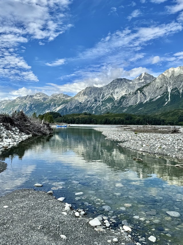 Serene river reflecting mountains and sky