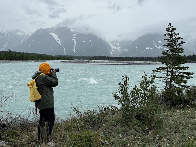 Person photographing a turquoise river