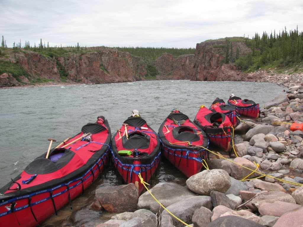 Red kayaks lined on rocky shore